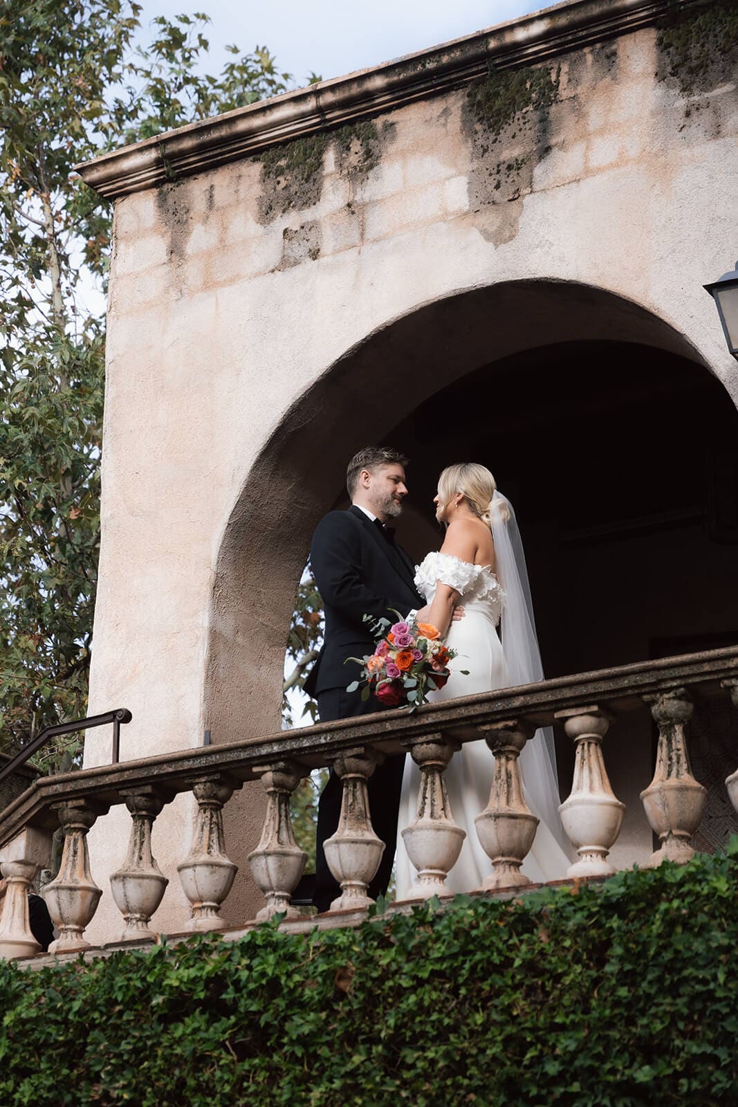 Bride and groom standing together on a balcony with ivy-covered walls and Spanish-style arches during a micro wedding at Tlaquepaque.