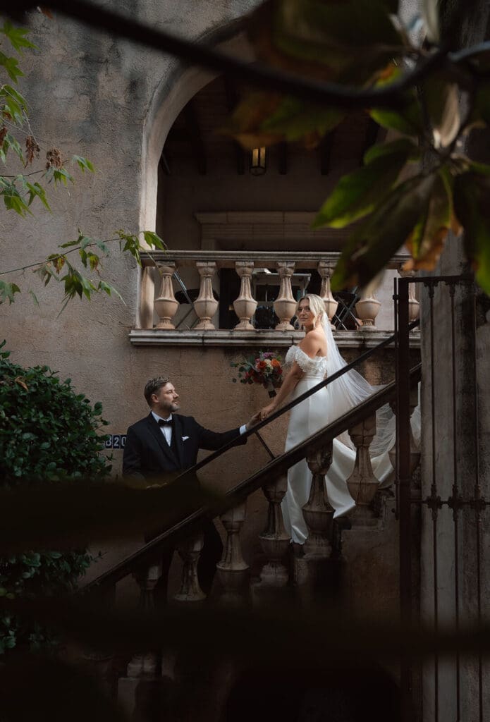 Bride walking down an outdoor staircase while the groom looks up at her from below.