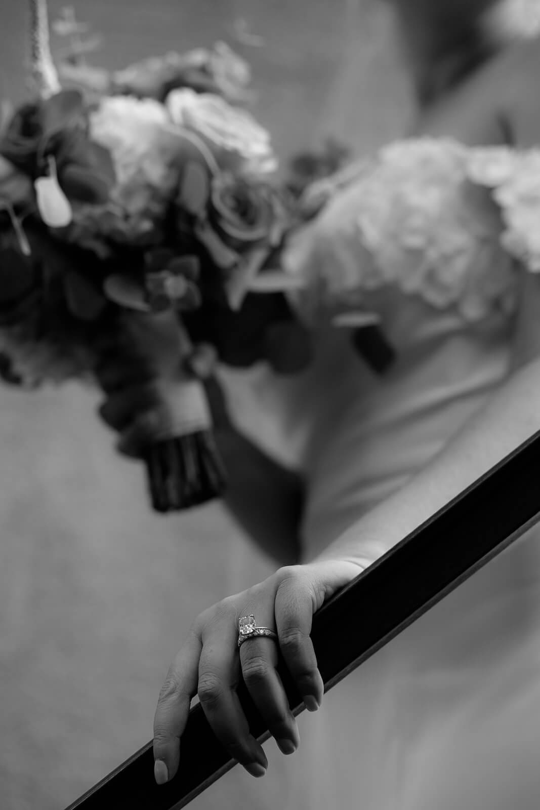 Black and white close-up photo of the bride holding her bouquet and resting her hand on a staircase railing during a micro wedding at Tlaquepaque.