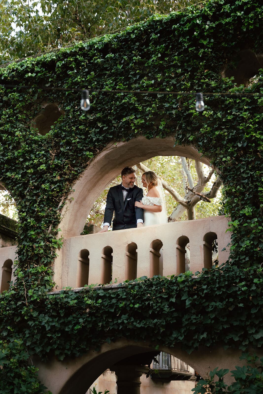 Bride and groom standing together on an ivy-covered balcony during a micro wedding at Tlaquepaque.