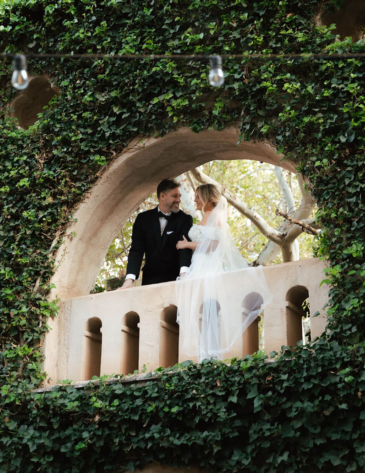 Bride and groom standing together on a balcony framed by ivy-covered arches during a micro wedding at Tlaquepaque.