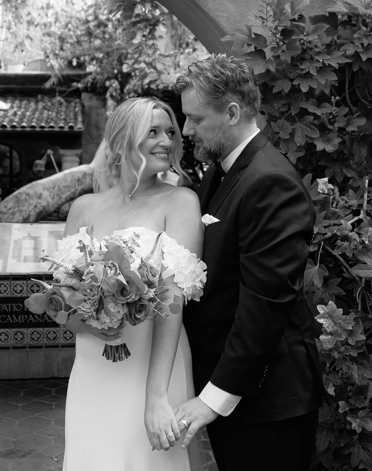 Black and white portrait of the bride and groom standing together outdoors holding hands during a micro wedding at Tlaquepaque.