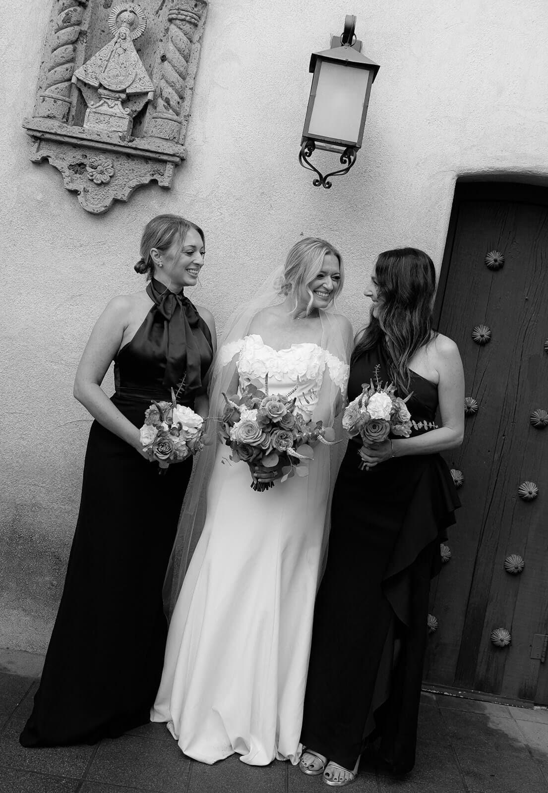 Black and white photo of the bride standing with two women holding bouquets during a wedding at Tlaquepaque.