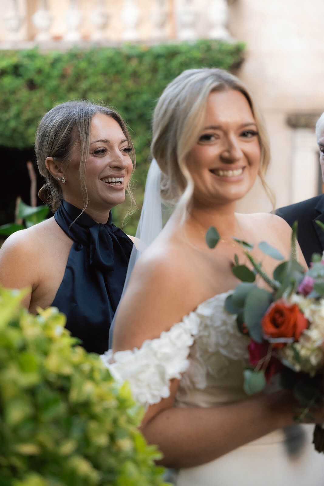 Bride smiling with her maid of honor before an intimate elopement ceremony in a historic courtyard