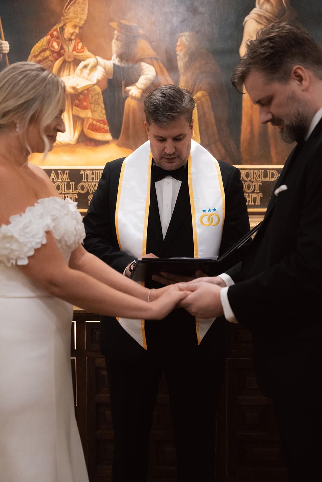 Couple holding hands during a traditional church elopement ceremony with officiant and warm candlelight