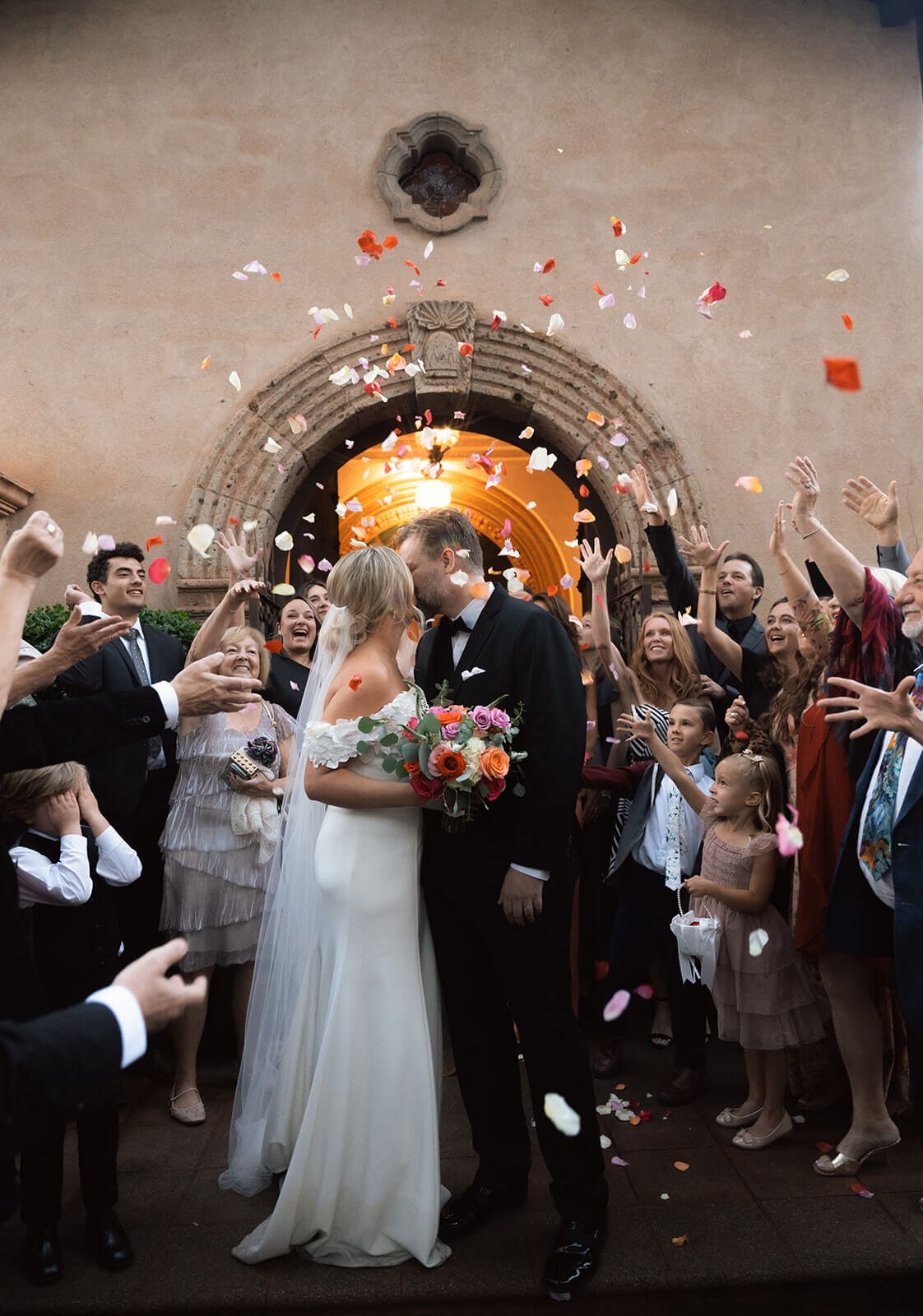 Bride and groom exiting the chapel while guests toss flower petals during a micro wedding at Tlaquepaque.