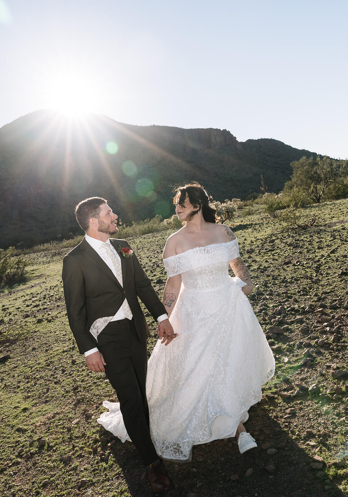 Couple walking hand in hand through the desert after their intimate Arizona wedding ceremony