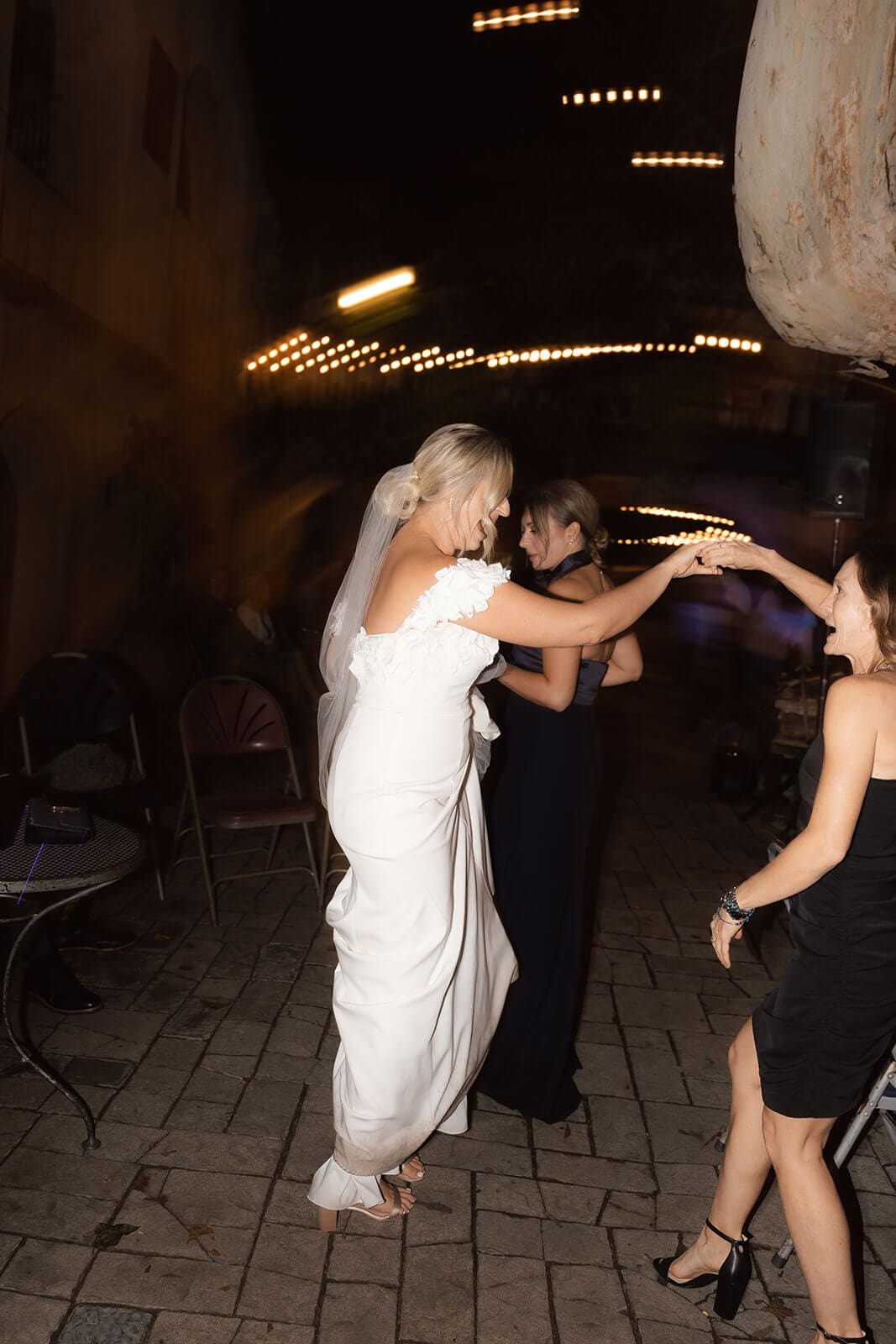 Bride dancing with guests during an outdoor reception at Tlaquepaque during the evening.
