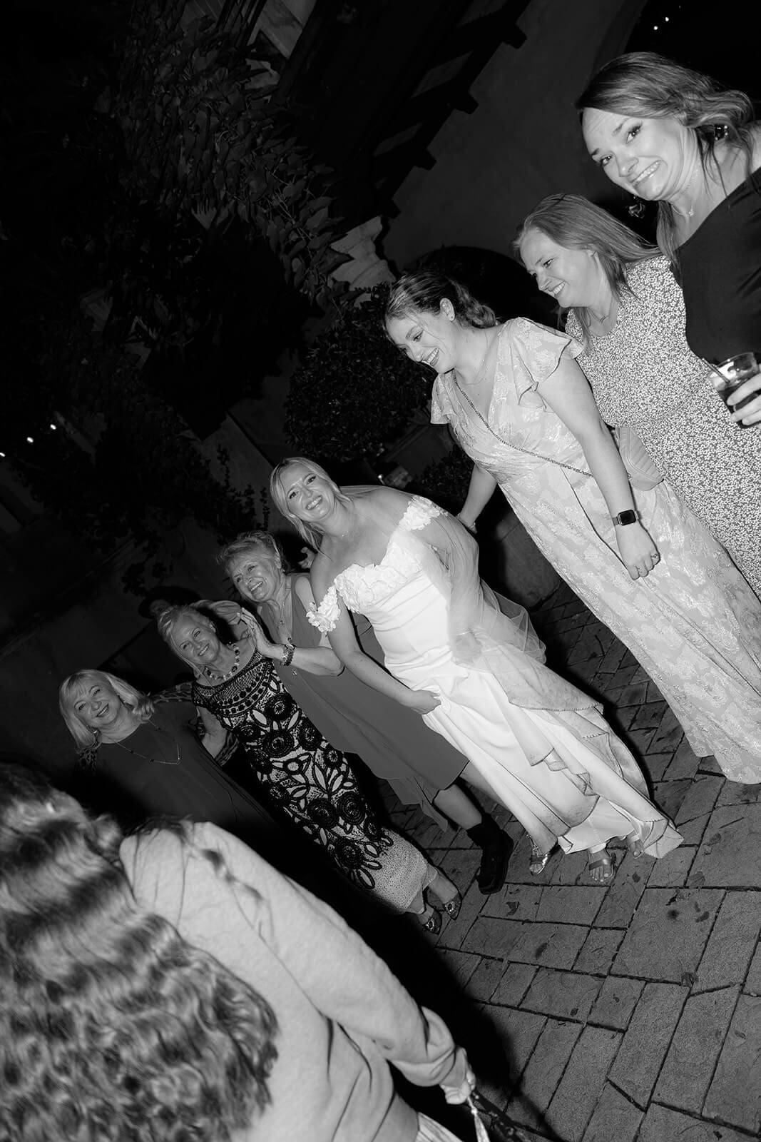 Black and white photo of guests dancing together during an outdoor wedding reception at Tlaquepaque.