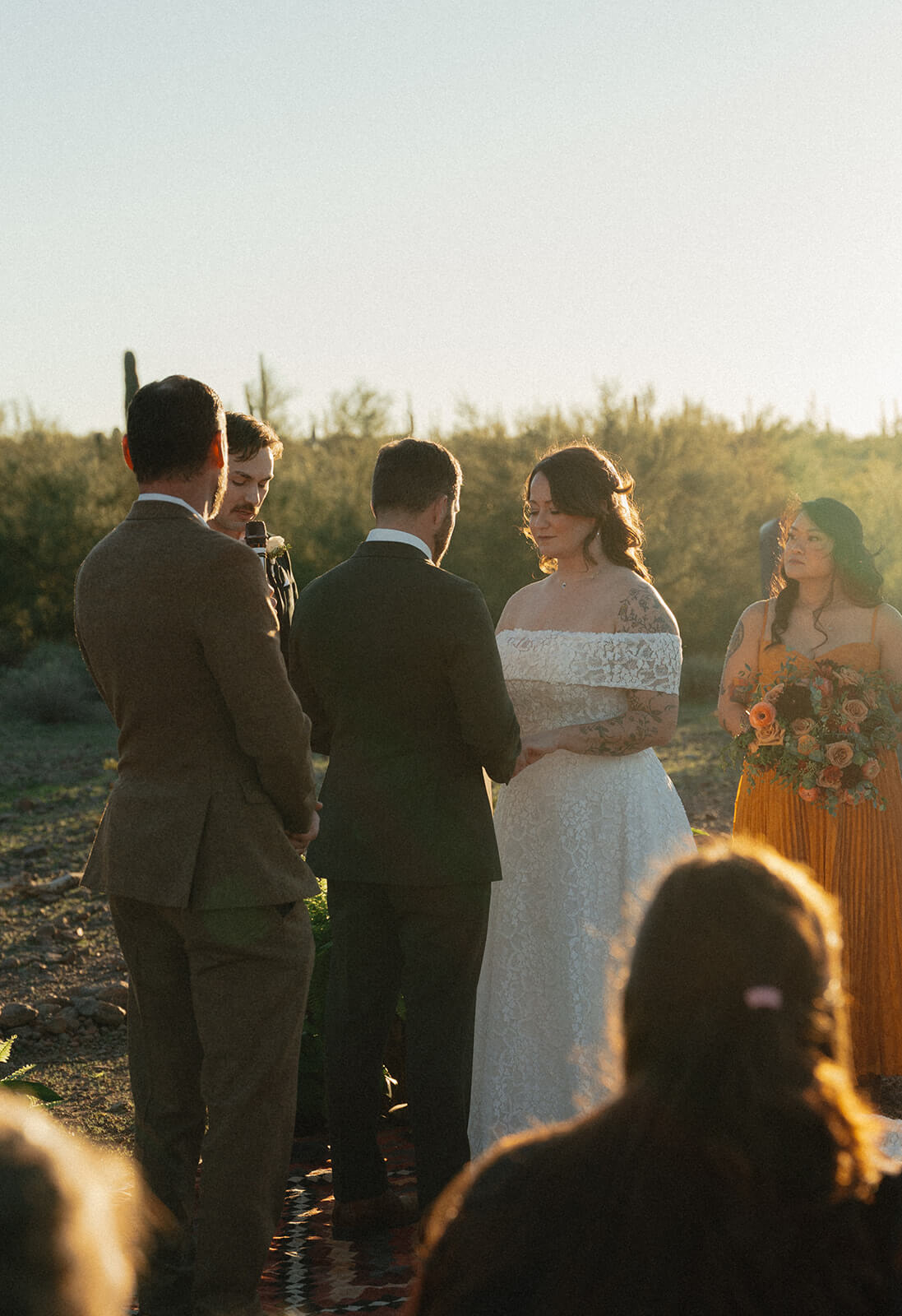Couple exchanging vows during a golden hour desert elopement ceremony surrounded by close family and warm sunset light
