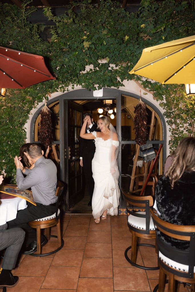 Bride dancing with guests during an outdoor wedding reception beneath string lights at night.