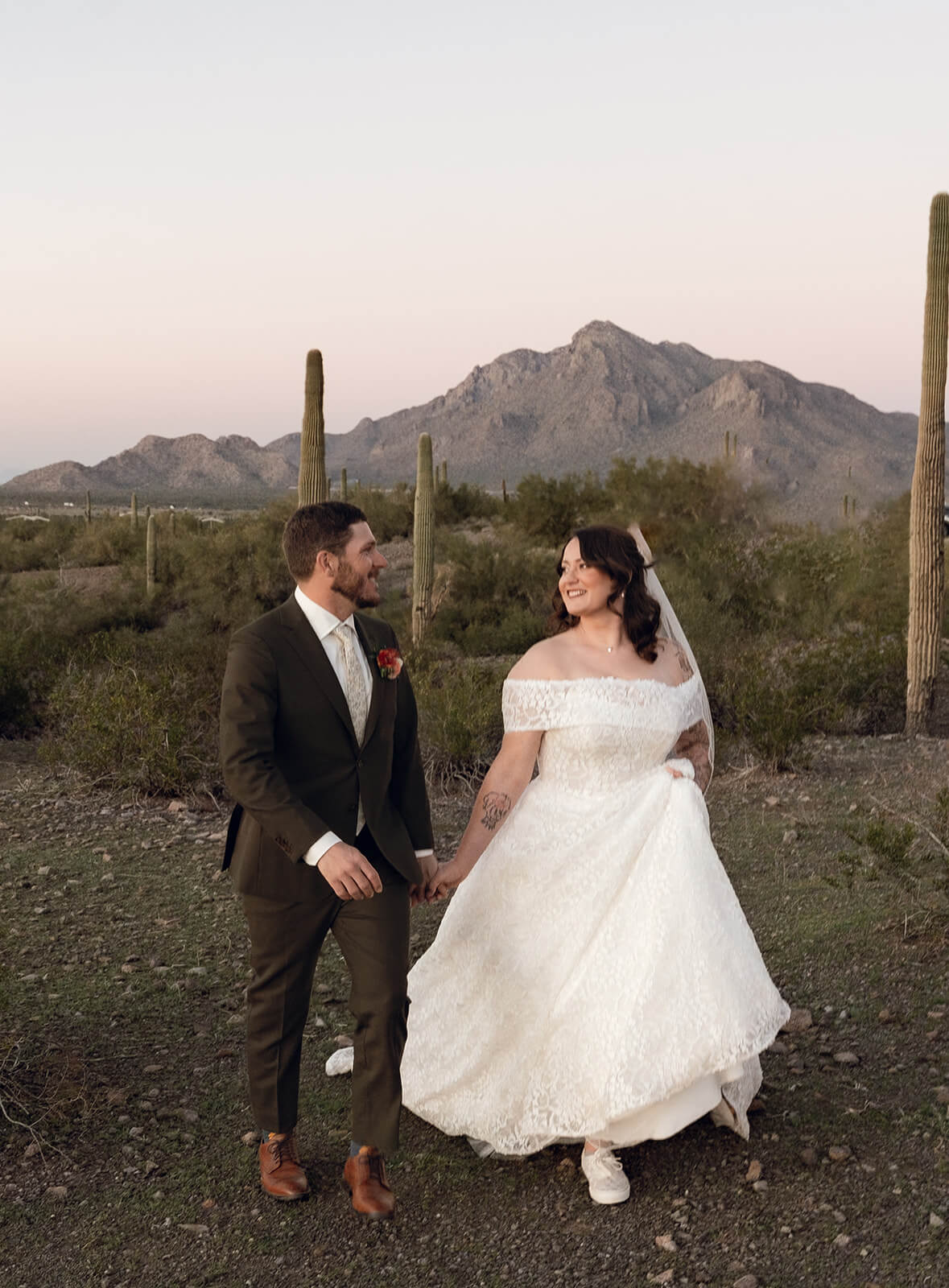 Couple walking together through the desert during a golden hour micro wedding with mountain views and cactus landscape