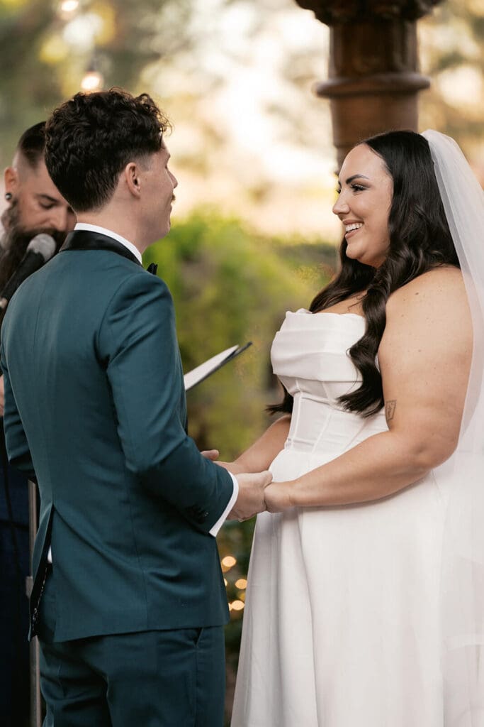 Bride and groom holding hands and exchanging vows during an intimate outdoor wedding ceremony.