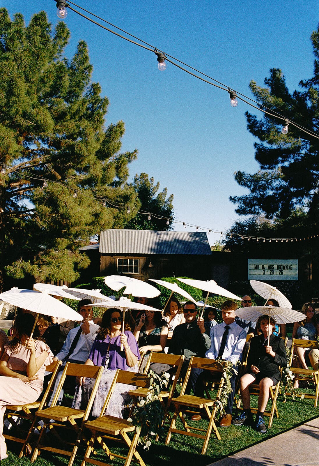 Guests gathered outdoors under umbrellas during cocktail hour at Shenandoah Mill wedding venue in Gilbert Arizona
