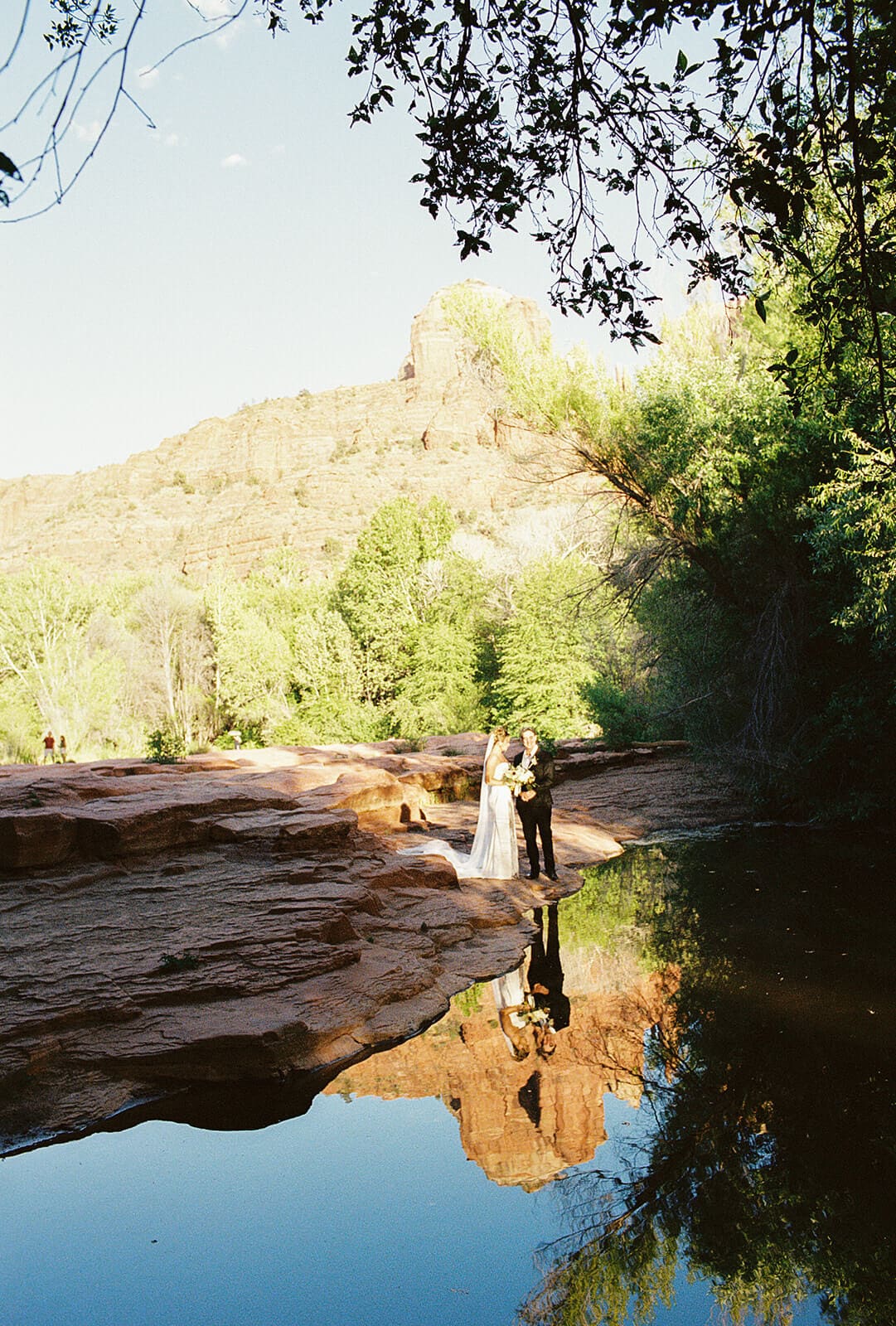 Scenic view of Sedona red rocks reflected in calm creek water during an intimate elopement day surrounded by desert greenery.