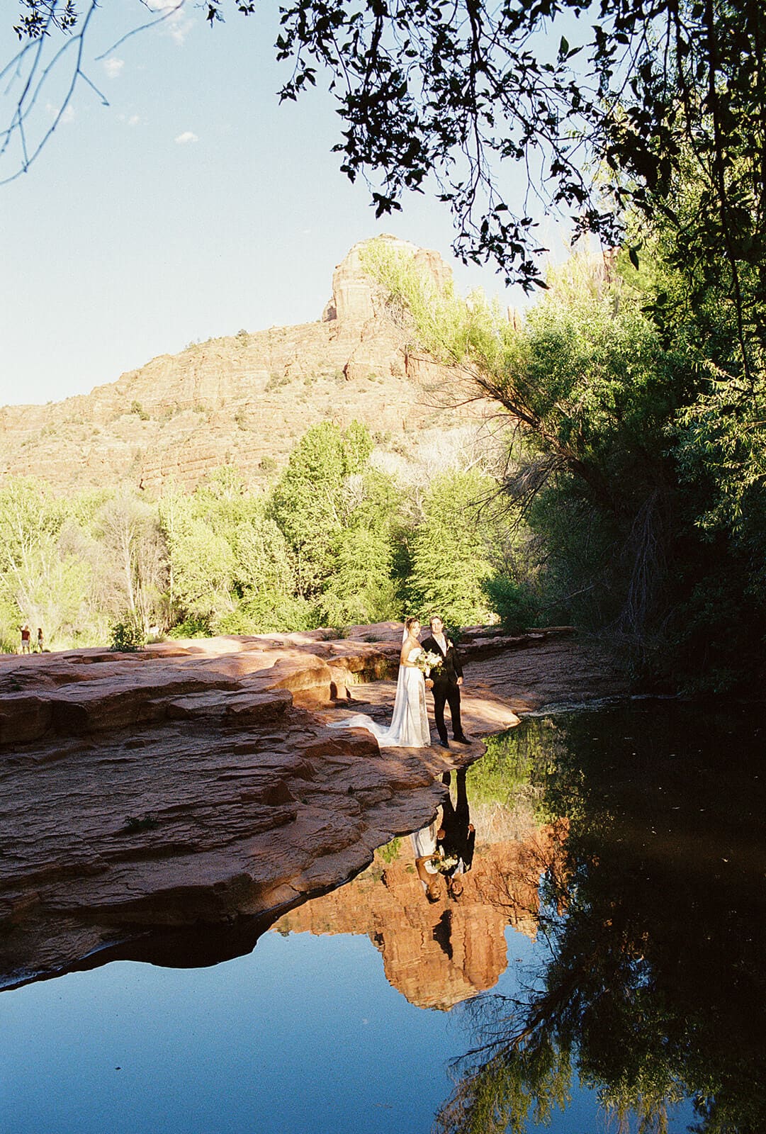 Scenic creek view with red rocks reflected in the water at a peaceful Sedona elopement location surrounded by trees.