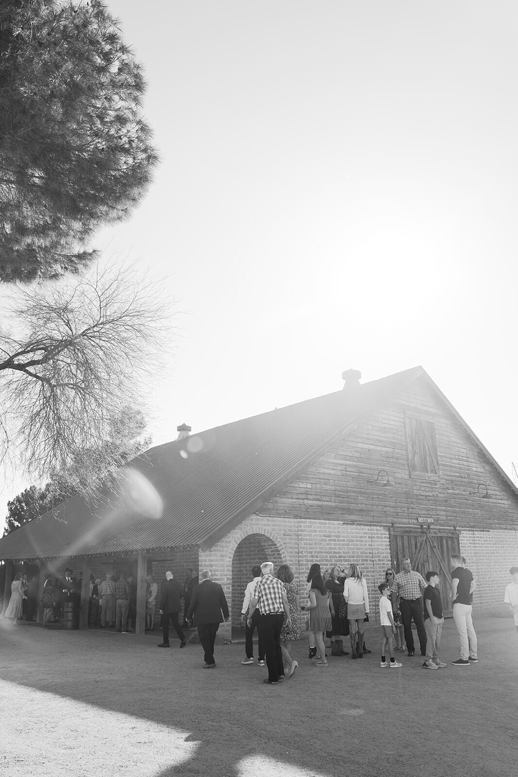 Black and white photo of guests gathered outside the historic manor building at Stonebridge Manor wedding venue in Mesa Arizona
