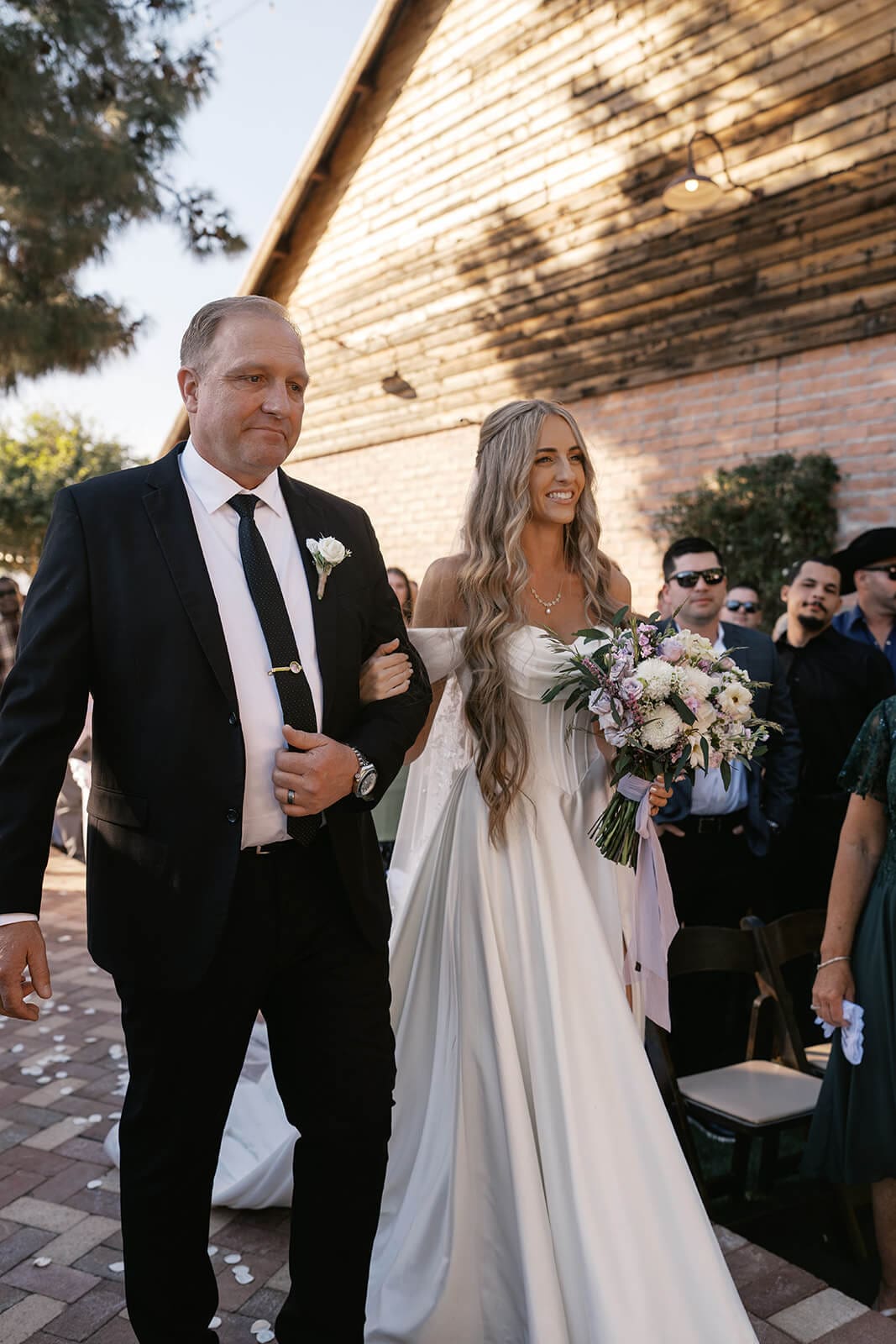 Bride walking down the aisle with her father during her ceremony at Stonebridge Manor garden wedding venue in Mesa Arizona
