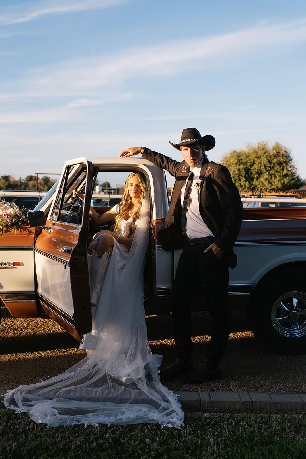 Bride stepping out of a vintage truck with a groom in a cowboy hat at Stonebridge Manor wedding venue in Mesa Arizona

