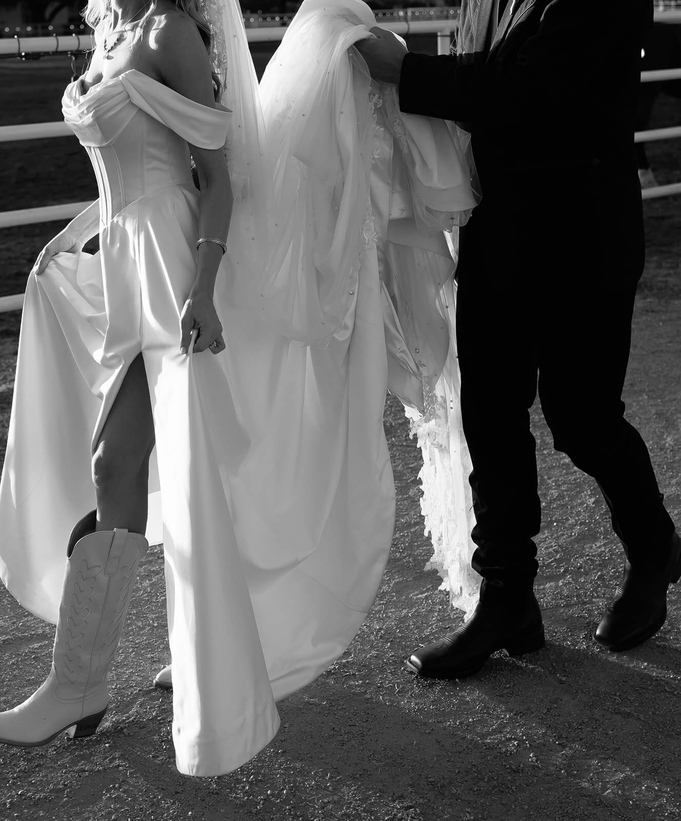 Black and white close up of bride and groom holding hands with her veil flowing between them at Saguaro Lake Guest Ranch wedding venue in Mesa Arizona

