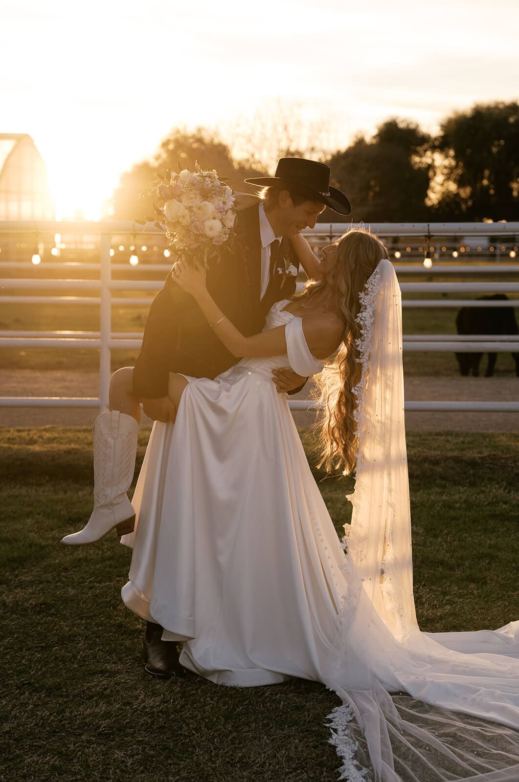 Bride and groom laughing together at golden hour near a fence line at Saguaro Lake Guest Ranch wedding venue in Mesa Arizona
