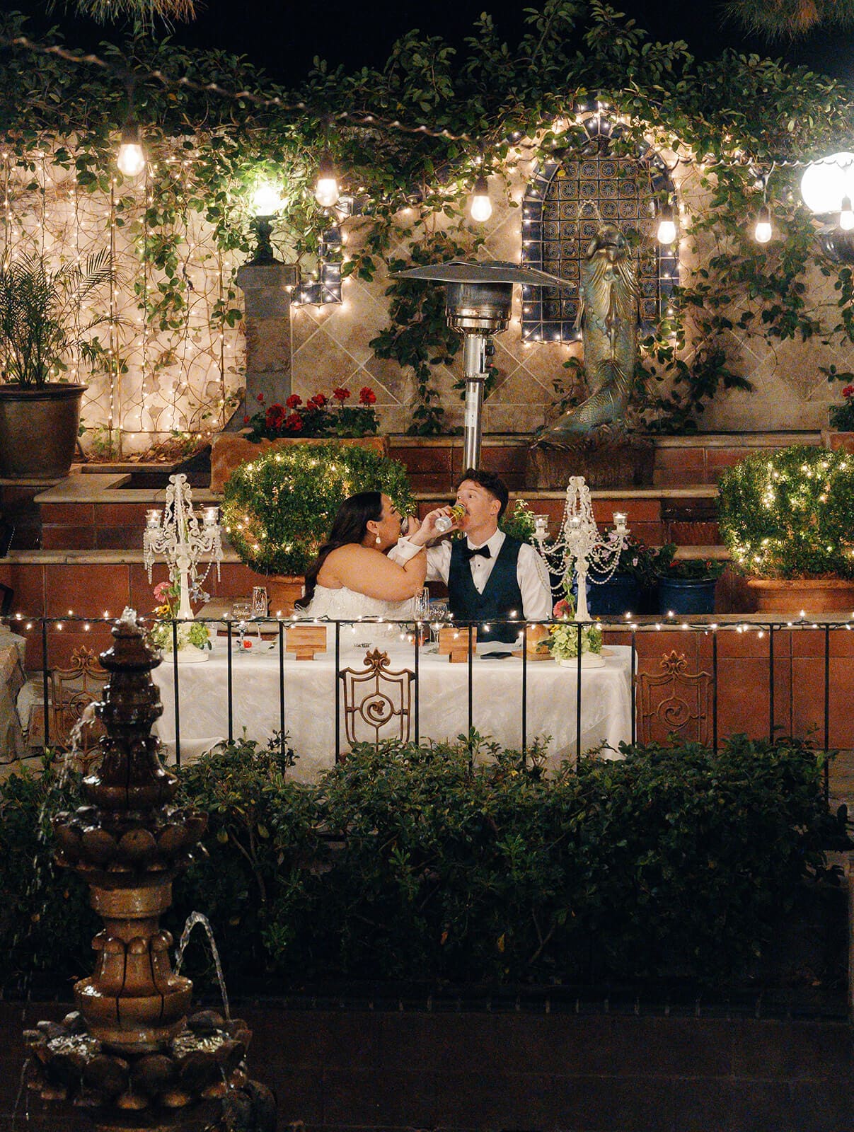 Bride and groom sharing a quiet moment together under string lights and ivy covered arches at The Wright House garden wedding venue in Mesa Arizona
