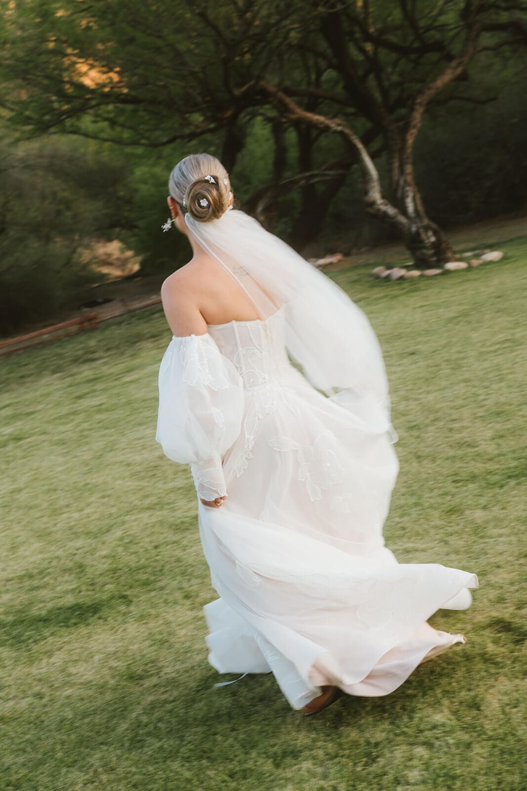 Bride standing alone with her veil blowing in the wind against the open landscape at Saguaro Lake Guest Ranch wedding venue in Mesa Arizona

