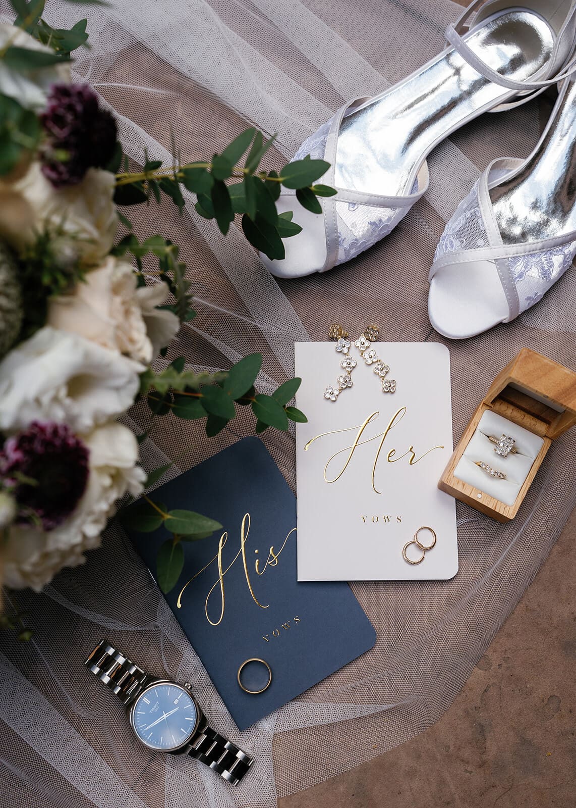 Close-up of wedding rings, vow books, white shoes, flowers, and bridal details styled on red rocks for a elopement.