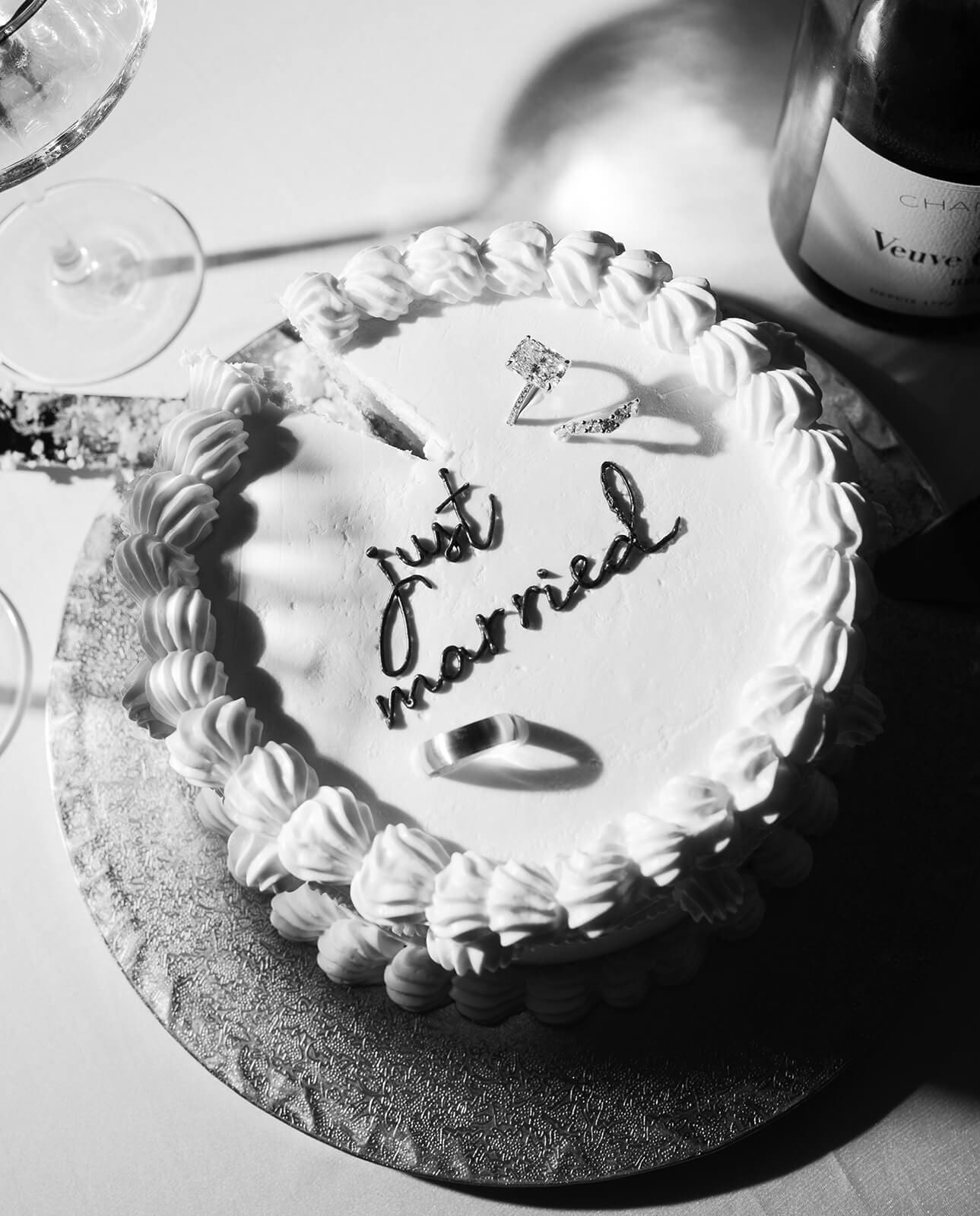 Close-up of a round “just married” cake with vintage-style piping from an intimate elopement celebration after the ceremony.