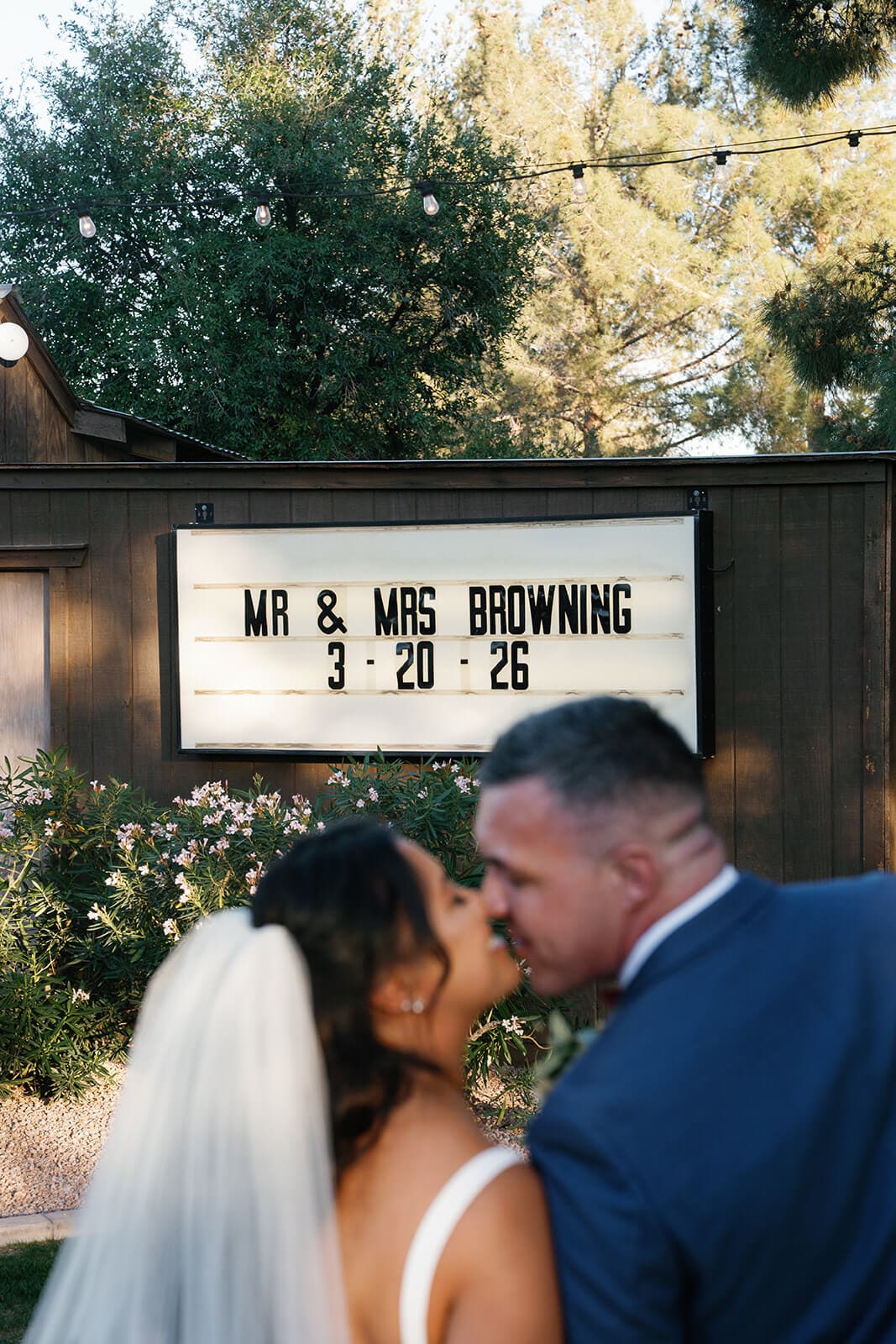 Bride and groom sharing a kiss in front of a marquee sign reading Mr and Mrs Browning at Shenandoah Mill garden wedding venue in Gilbert Arizona
