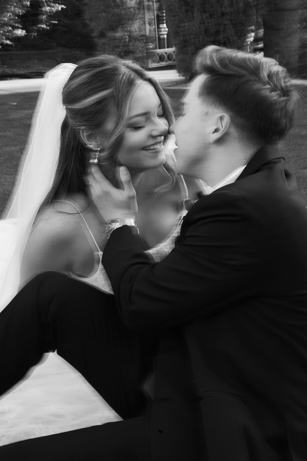 Bride and groom sharing a close embrace during wedding portraits on the lawn at Stonebridge Manor, photographed in black and white.