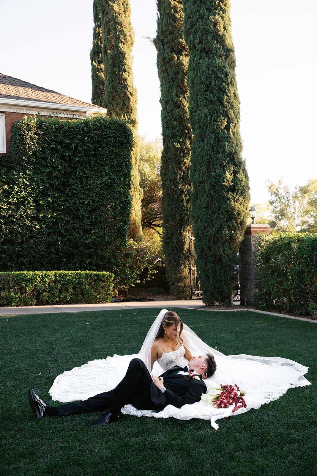 Bride and groom sitting together on the lawn with her dress spread around them at Stonebridge Manor wedding venue in Mesa Arizona
