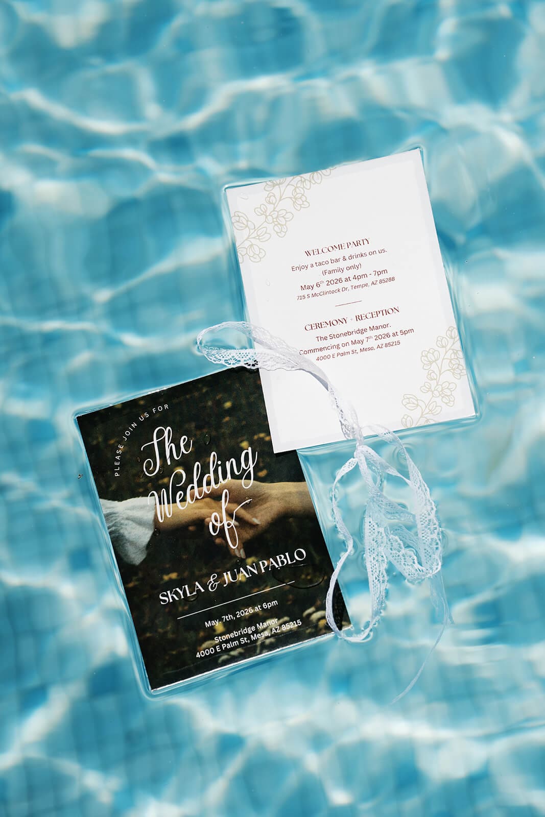 Wedding invitation suite floating in the blue-tiled pool at Stonebridge Manor, featuring custom stationery and lace ribbon details.