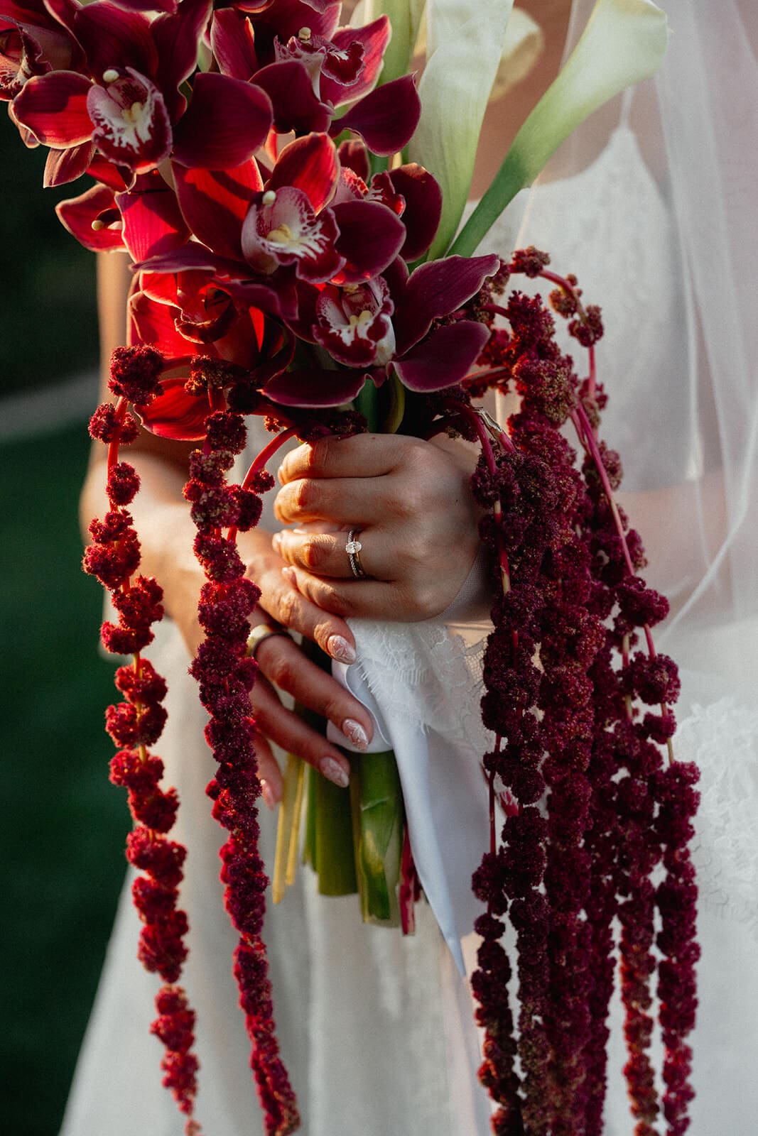 Close-up portrait of the bride holding a cascading burgundy orchid bouquet with calla lilies during her Stonebridge Manor wedding.