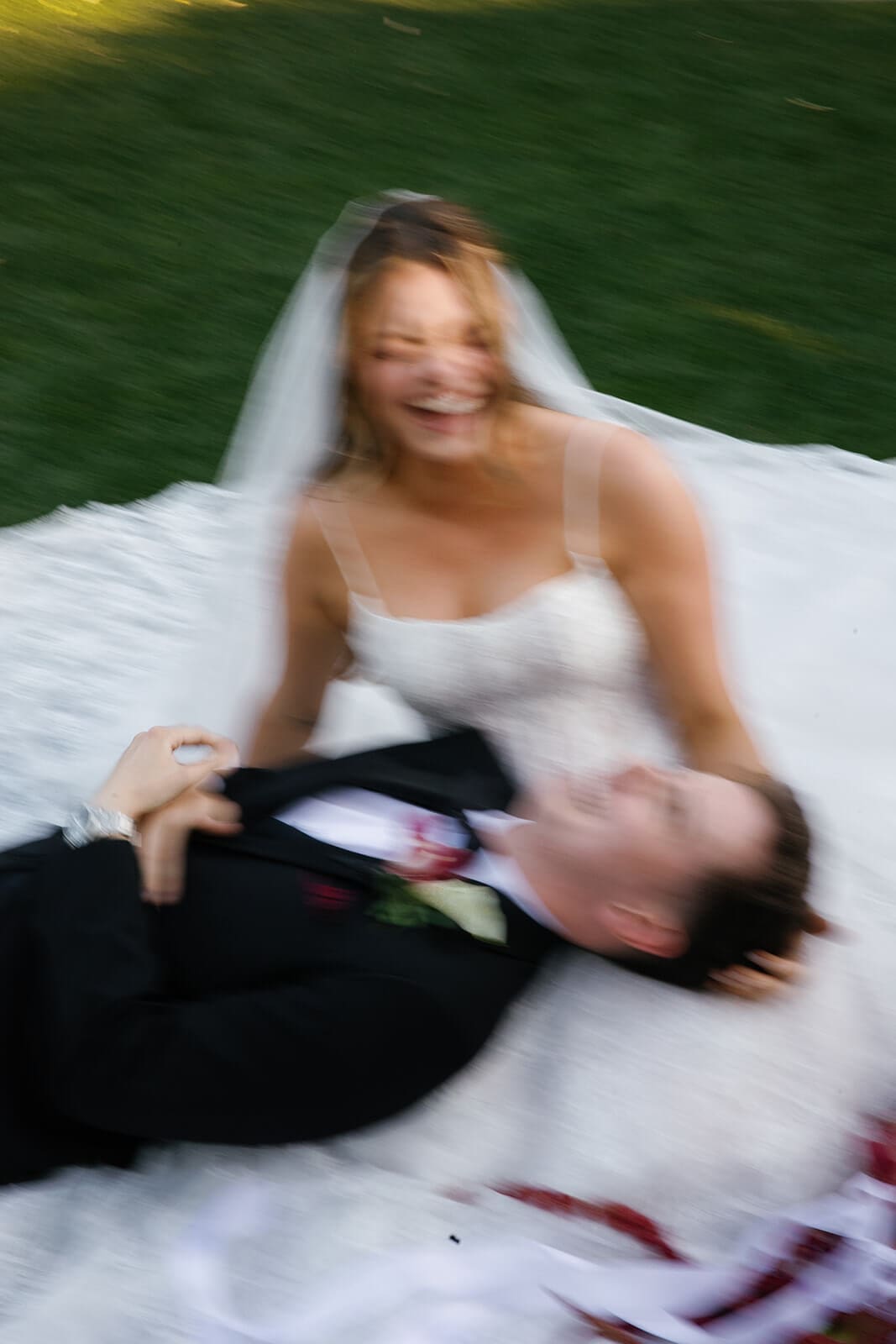 Creative motion-blur portrait of the bride and groom lying on the bride’s veil during sunset portraits at Stonebridge Manor.