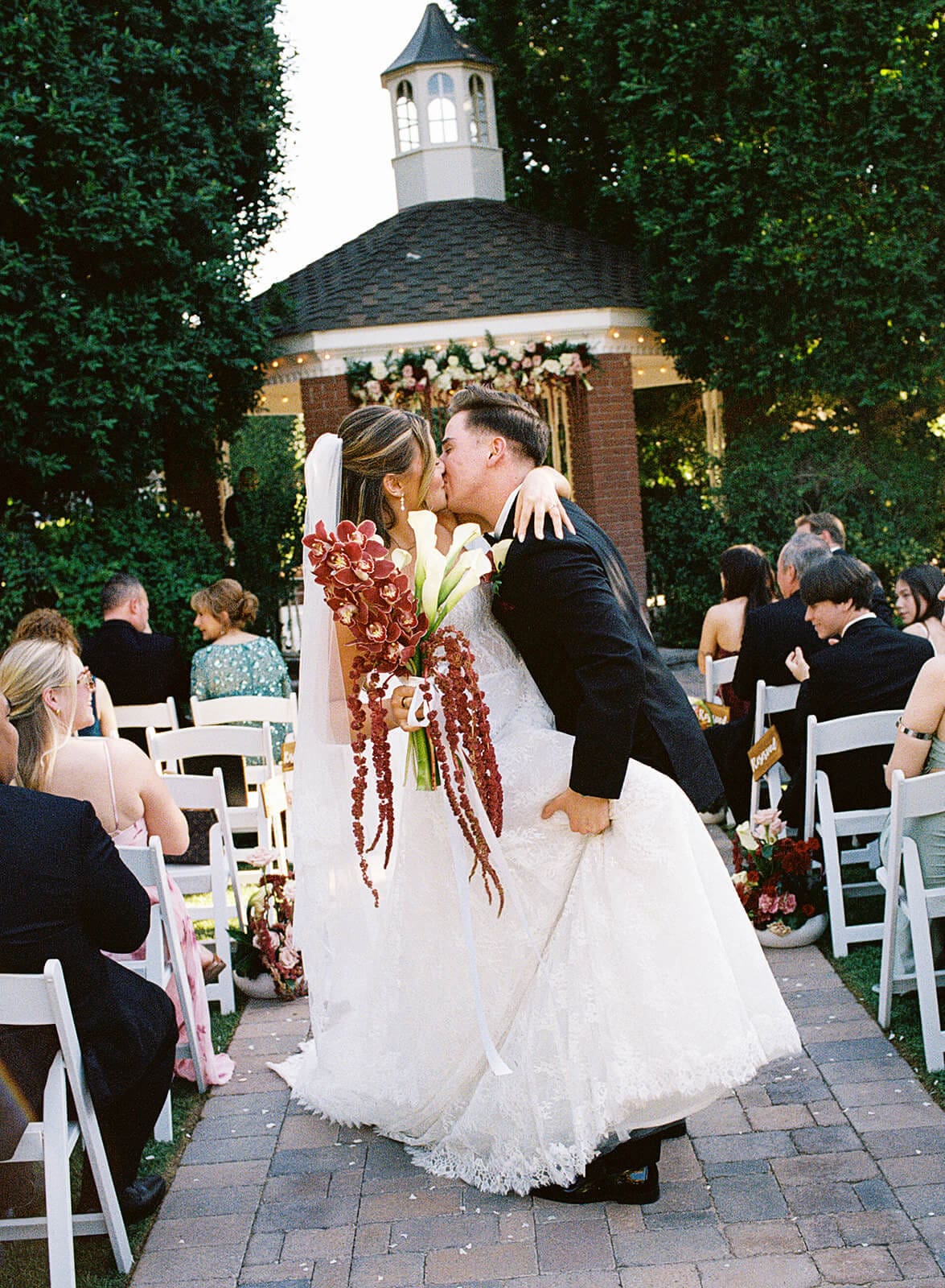 Bride and groom sharing a kiss while walking down the aisle after their outdoor wedding ceremony at Stonebridge Manor.