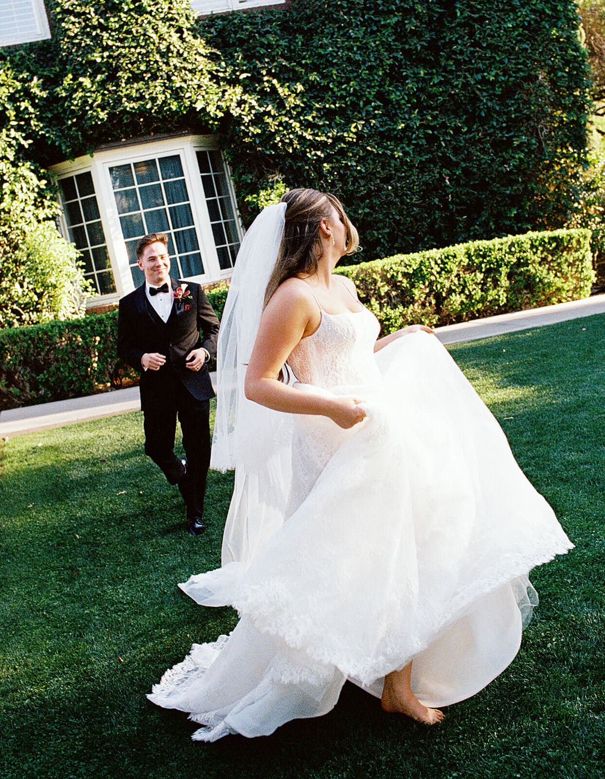 Bride twirling across the lawn while the groom follows behind during playful sunset portraits at Stonebridge Manor.