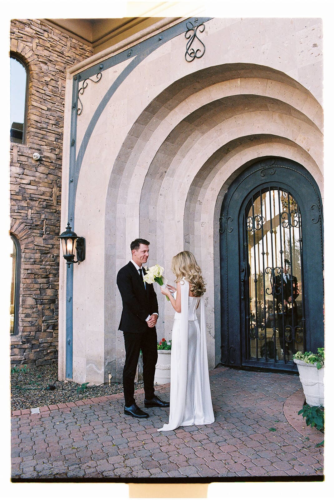 Bride and groom standing together outside an arched doorway at their Arizona Airbnb wedding venue.