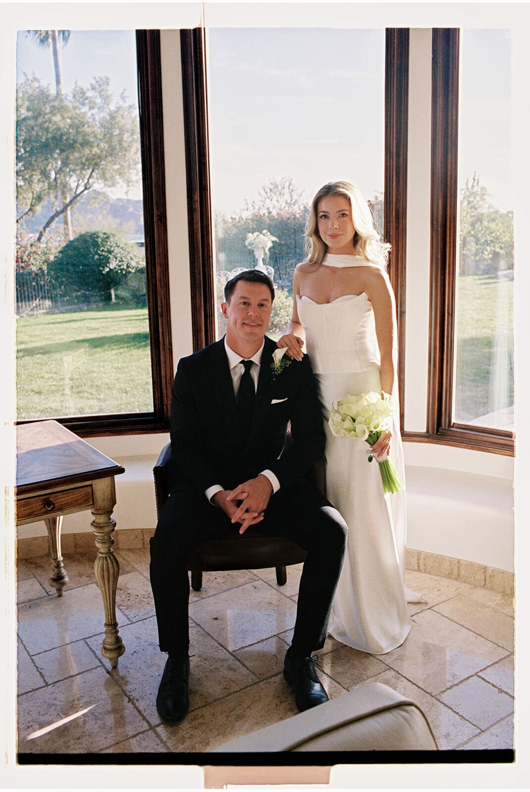 Bride and groom posing inside a bright Airbnb wedding venue with large windows, desert views, and soft natural light.