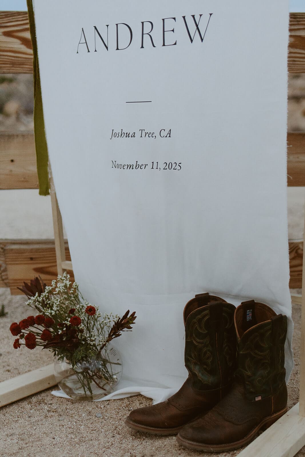 Custom wedding welcome sign with cowboy boots and flowers at a Joshua Tree Airbnb wedding.