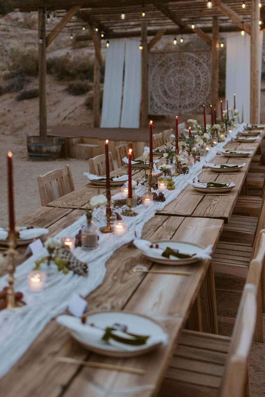 Candlelit desert Airbnb wedding reception table set under string lights and a wooden pergola.