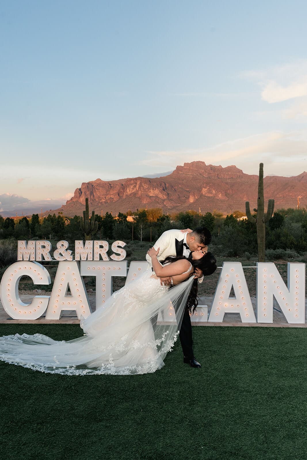 Groom dipping the bride beside a personalized Mr. and Mrs. wedding sign in Arizona.