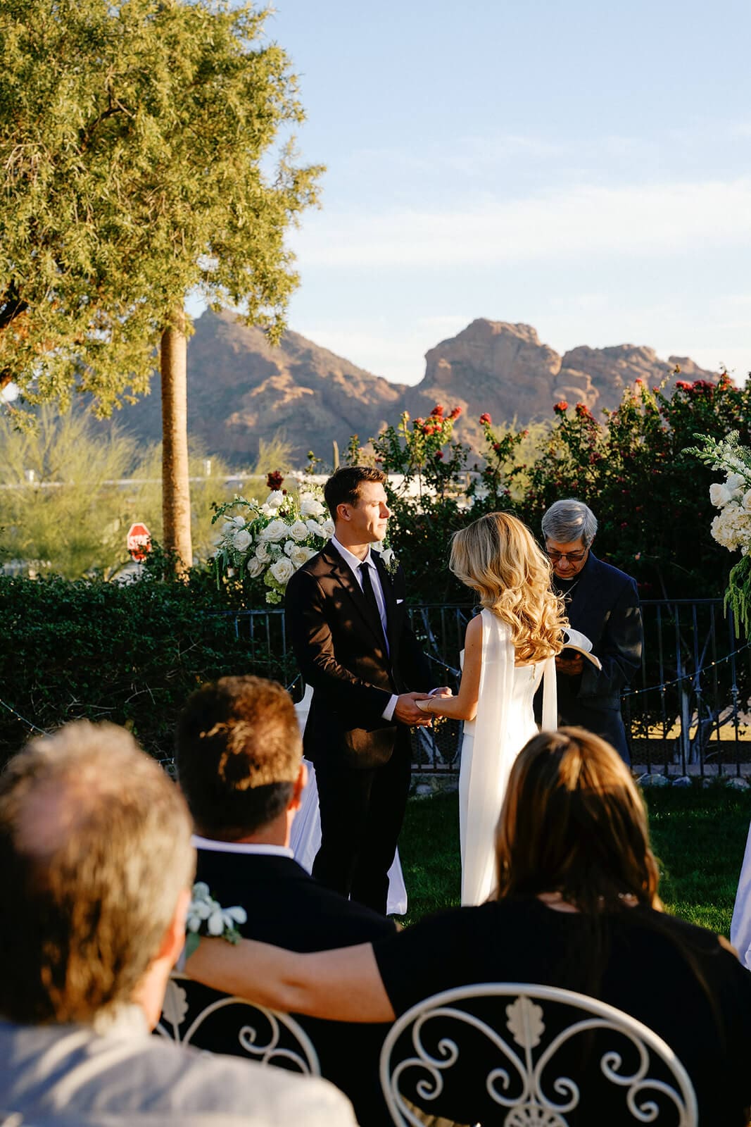 Bride and groom exchanging vows during an intimate Airbnb wedding ceremony with mountain views and guests seated nearby.