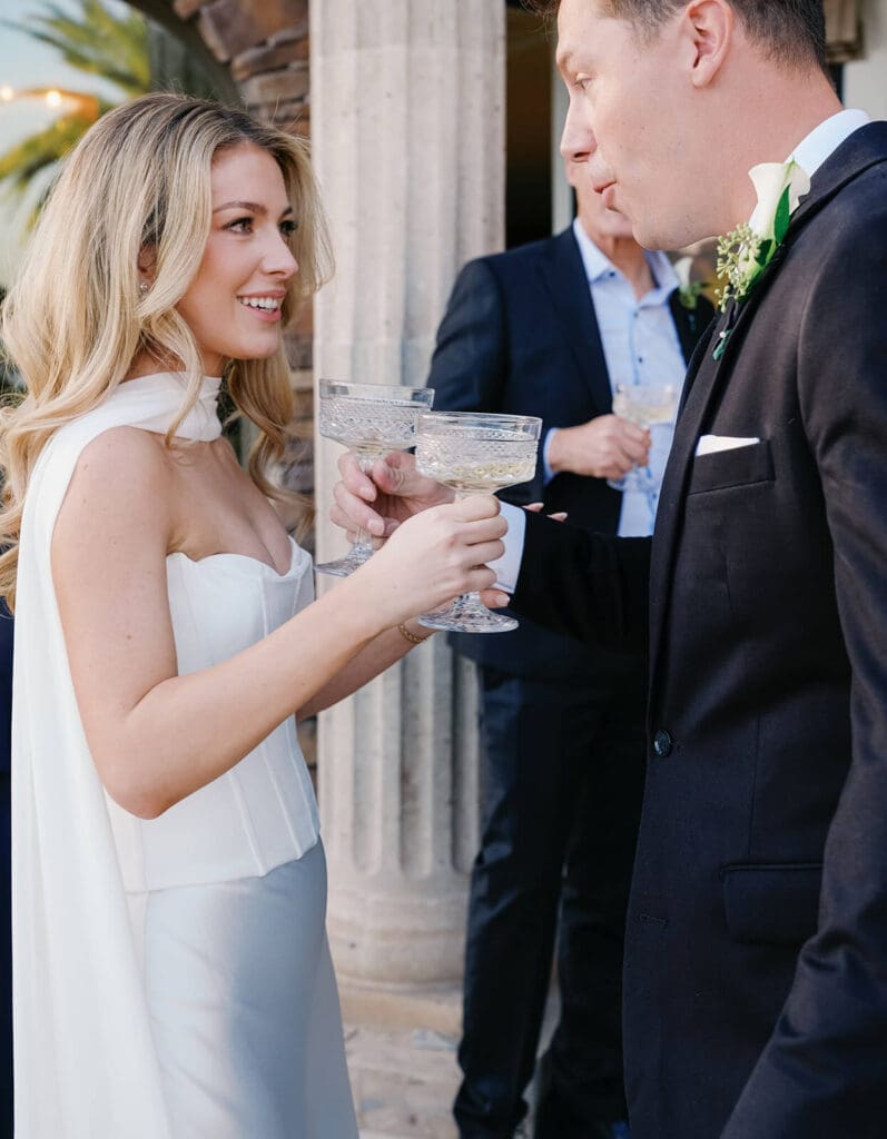 Bride and groom clinking champagne coupes with guests after their intimate Airbnb wedding ceremony.