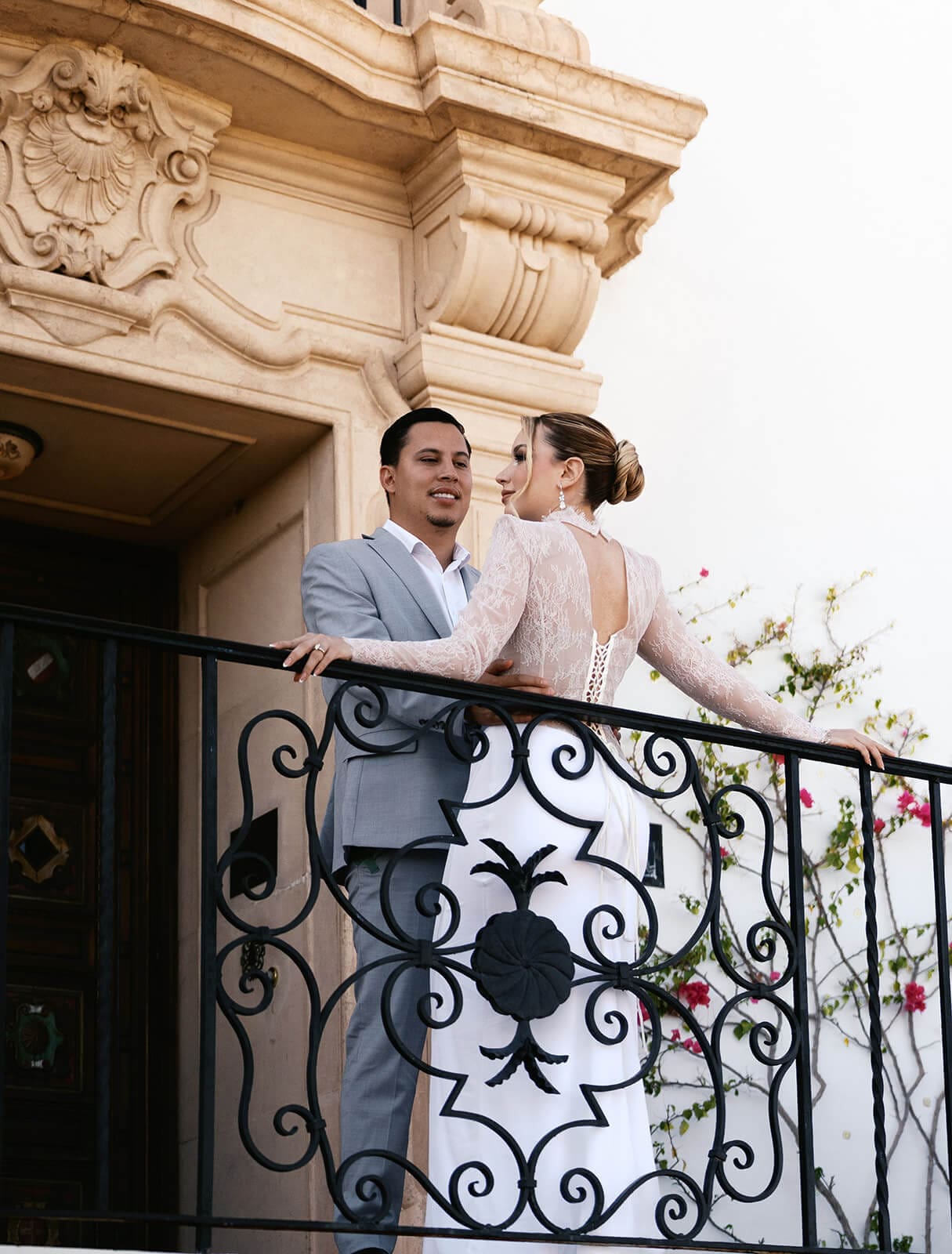Newlyweds laughing together on an ornate balcony at a Spanish-style Arizona wedding venue.