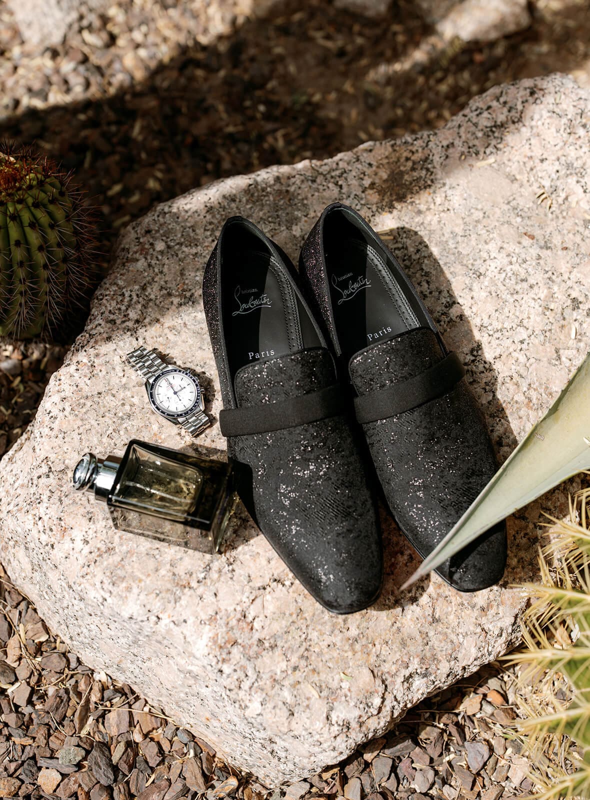 Black groom’s loafers, watch, and cologne arranged on a rock before a Boulders Resort wedding.