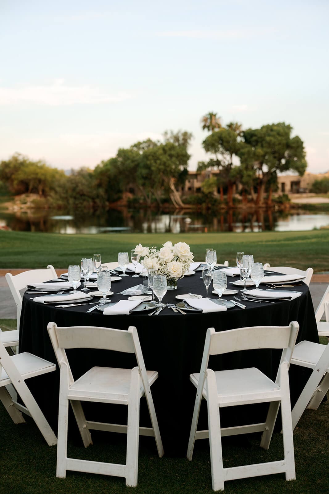 Black-and-white wedding reception table with white floral centerpieces overlooking the water and golf course.