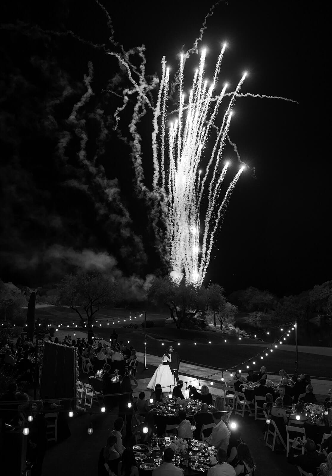 Black-and-white photo of fireworks lighting the sky above an outdoor wedding reception and dance floor at The Boulders Resort.