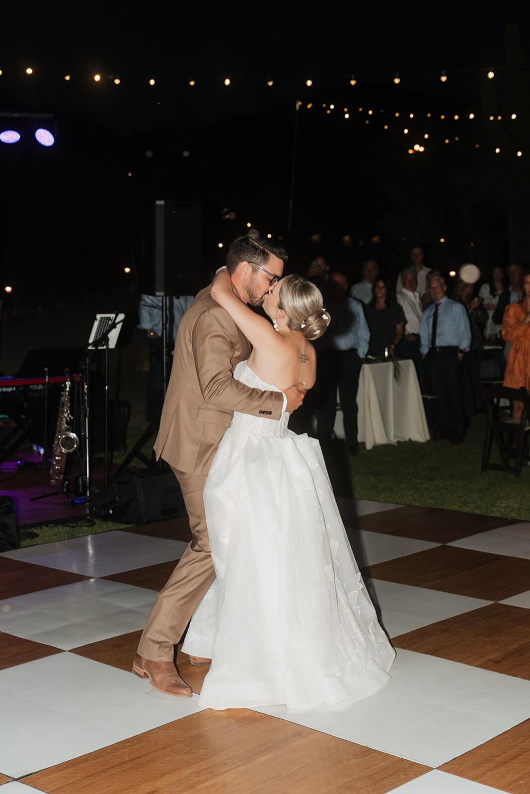 Bride and groom share their first dance beneath string lights during an outdoor Arizona wedding reception.