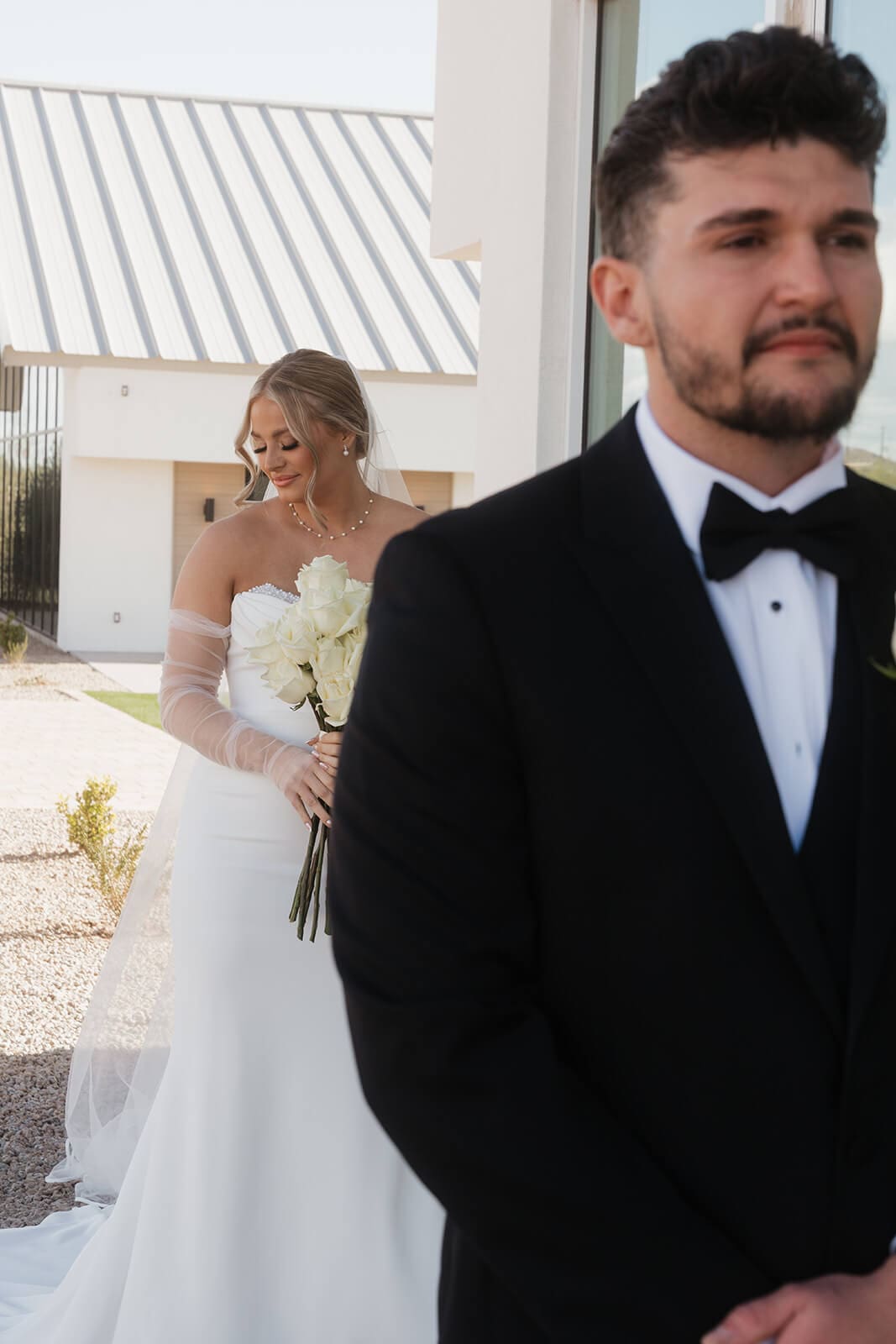 Groom waits for the bride during their first look outside a modern Arizona wedding venue.